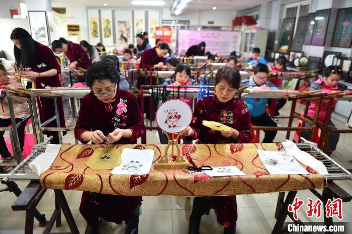 江西省級(jí)非遺豫章繡傳承人手把手指導(dǎo)小學(xué)生繡制2022年北京冬奧會(huì)吉祥物“冰墩墩”形象。　喻云亮 攝