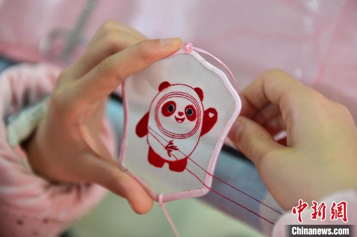 圖為一名小學(xué)生正在繡制2022年北京冬奧會(huì)吉祥物“冰墩墩”形象?！∮髟屏?攝