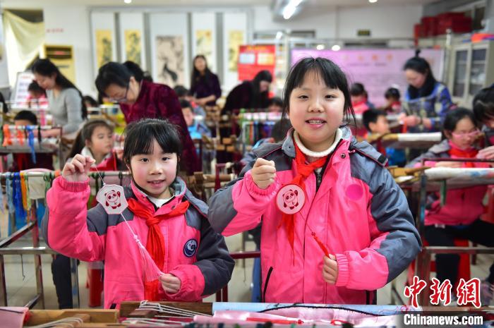 圖為小學(xué)生展示繡制好的2022年北京冬奧會(huì)吉祥物“冰墩墩”形象。　喻云亮 攝