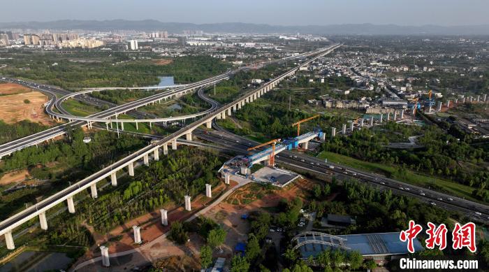 航拍正在建設(shè)的跨越成都繞城高速公路連續(xù)梁施工現(xiàn)場，旁邊依次為已運(yùn)營的成渝高速鐵路和機(jī)場高速公路?！⒅铱?攝
