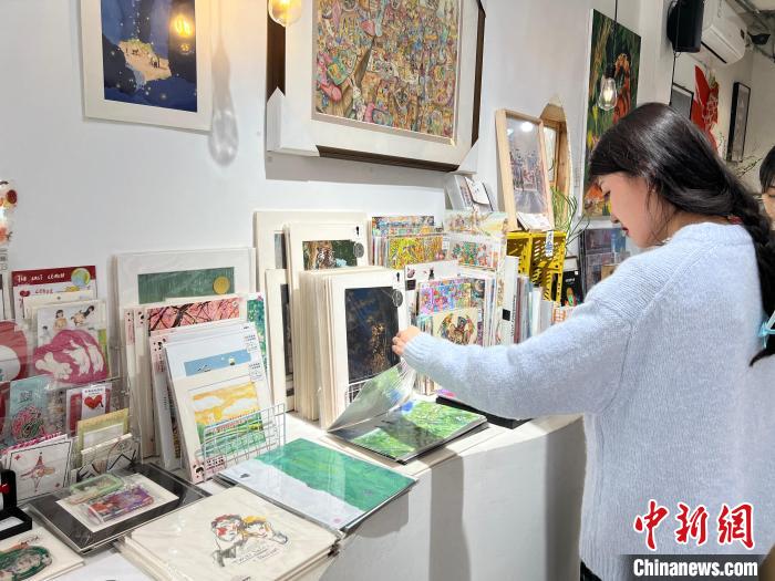 圖為藝術(shù)品商店內(nèi)，顧客挑選插畫作品?！＄婌?攝