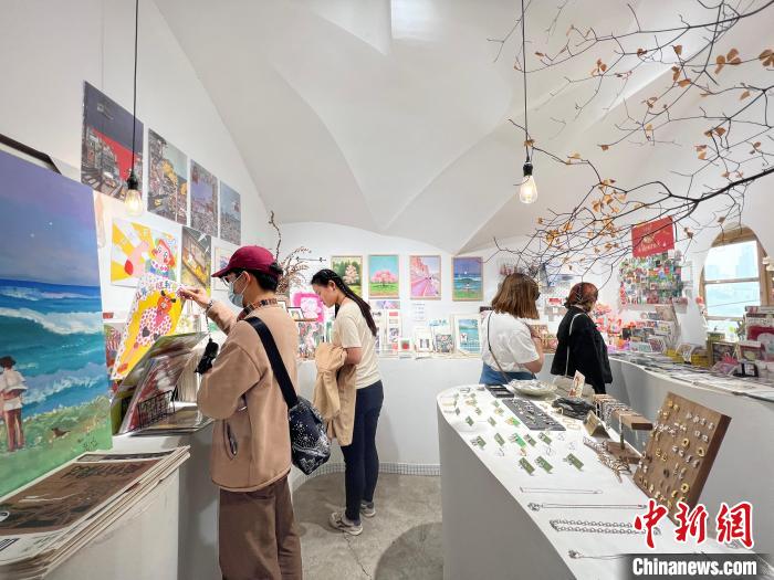圖為藝術(shù)品商店內(nèi)，顧客挑選插畫作品?！＄婌?攝