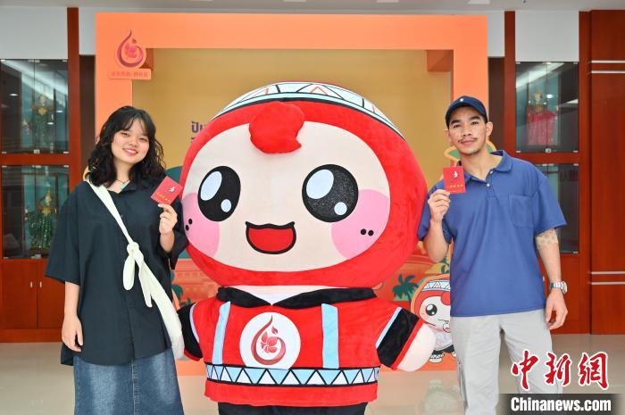 圖為泰國(guó)留學(xué)生手持獻(xiàn)血證與人偶合影?！∮峋?攝