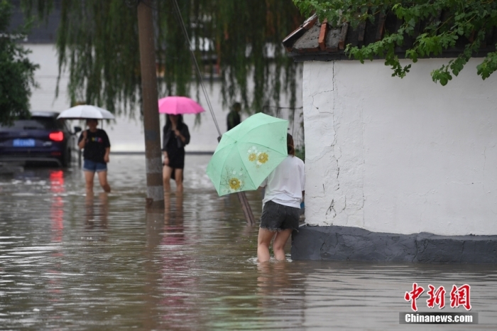 7月31日，市民行走在雨中的北京房山區(qū)瓦窯頭村。北京市氣象臺當日10時發(fā)布分區(qū)域暴雨紅色預(yù)警信號。北京市水文總站發(fā)布洪水紅色預(yù)警，預(yù)計當日12時至14時，房山區(qū)大石河流域?qū)⒊霈F(xiàn)紅色預(yù)警標準洪水。<a target='_blank' href='/'><p  align=