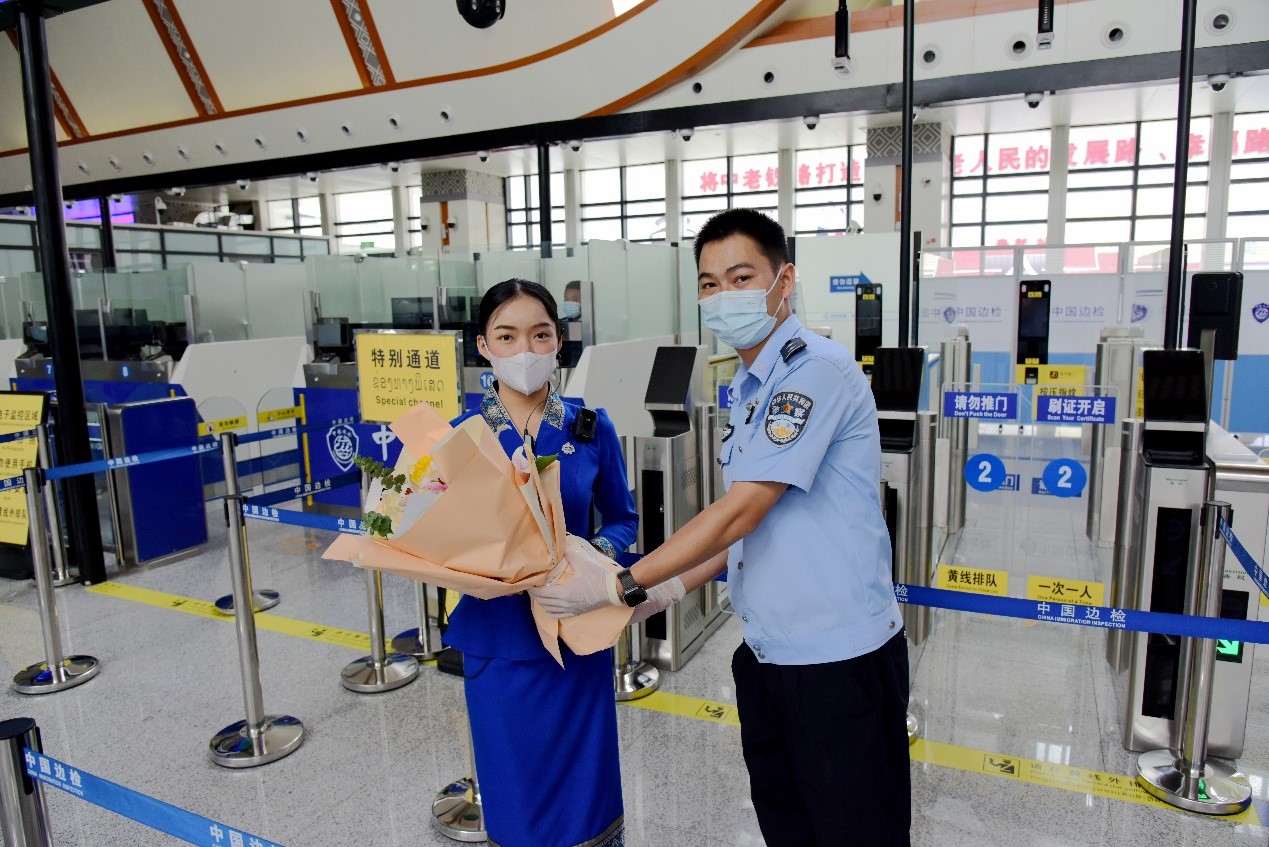 磨憨出入境邊防檢查站民警為中老鐵路第100萬名出入境旅客，D888次國際旅客列車老撾籍乘務(wù)員森達拉·妮緹婭（Sengdala Nitiya），送上鮮花。黃遠飛 攝