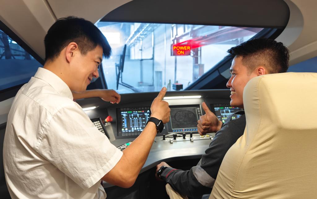 8月25日，在印度尼西亞萬隆的雅萬高鐵德卡魯爾動車所內(nèi)，中國師傅穆振（左）在向印尼火車司機(jī)塞蒂亞萬講解動車組出庫前的上電作業(yè)。