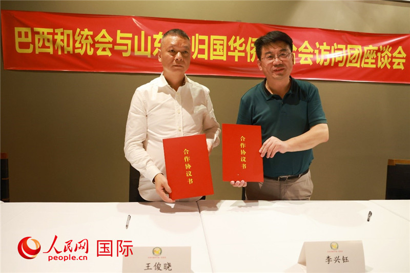 中國僑聯(lián)副主席、山東省僑聯(lián)主席李興鈺（右）與巴西和統(tǒng)會會長王俊曉簽署合作協(xié)議書。人民網(wǎng)記者 陳海琪攝