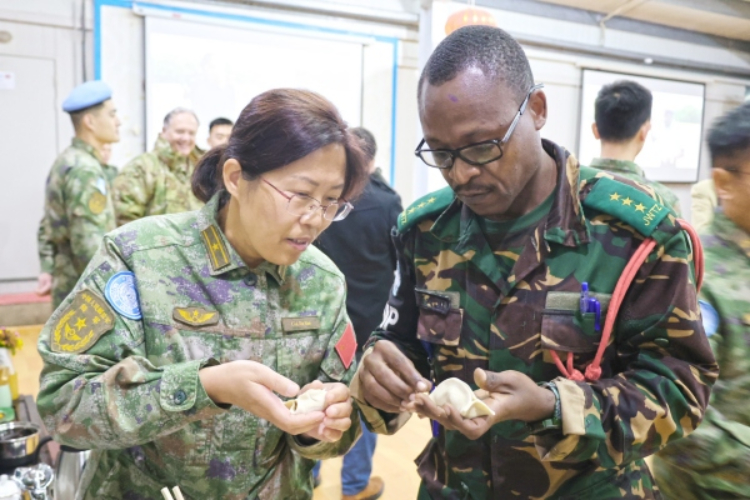 圖為維和官兵與外軍人員共同包餃子。胡光明攝