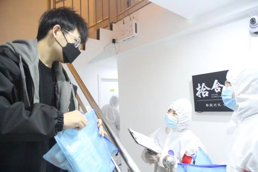 社區(qū)工作人員和志愿者身穿防護(hù)服上門送馬應(yīng)龍大健康防疫包。徐帥攝