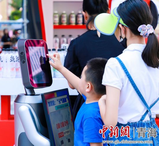 圖為一名小朋友正在和機(jī)器人“志愿者”進(jìn)行互動(dòng)。 沐聞 攝