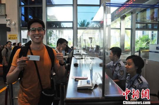  4月30日上午，從美蘭機場入境的新加坡旅客接過?？诿捞m邊檢站民警的溫馨提示小卡片后豎起大拇指點贊?！±盍濉z