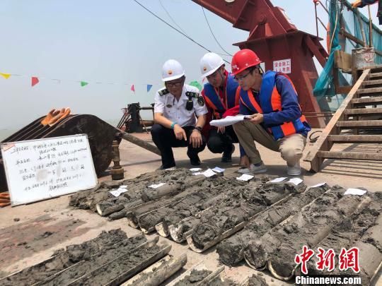 圖為勘察設(shè)計人員與海事局工作人員查看巖芯情況。　魏震 攝