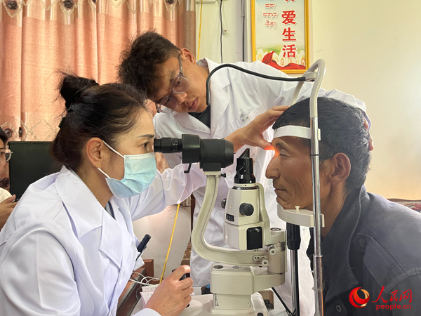 王紅英（左）和團(tuán)隊(duì)成員為達(dá)熱村村民檢查眼睛。人民網(wǎng)記者 杜燕飛攝