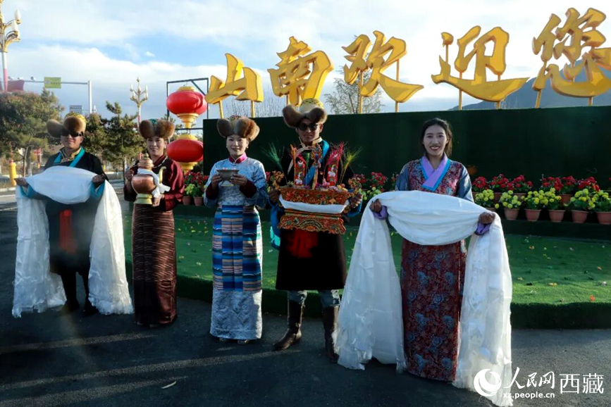 扎西曲登社區(qū)的居民在“山南歡迎您”標(biāo)志前，手持潔白哈達(dá)和切瑪，列隊迎接來自區(qū)內(nèi)外的游客，用最隆重的禮儀開啟一場沉浸式藏歷新年民俗體驗之旅。人民網(wǎng)記者 吳雨仁攝