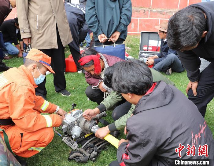 圖為森林消防員為護(hù)林員講解滅火裝備的使用方法?！〔际猩窒乐ш?duì) 供圖