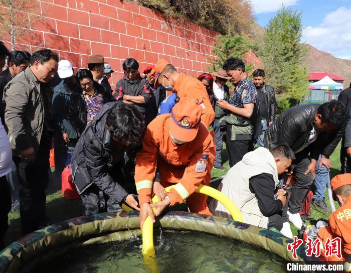 圖為森林消防員為護(hù)林員講解滅火裝備的使用方法?！〔际猩窒乐ш?duì) 供圖