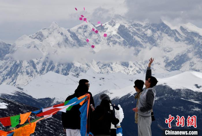 圖為5月14日，游客在西藏林芝色季拉山觀景臺拋灑“隆達”(風馬旗，藏族民眾的一種祈福方式)?！±盍?攝