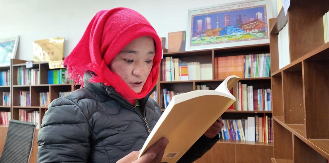 一名婦女正在認(rèn)真閱讀書籍。申扎縣融媒體中心供圖