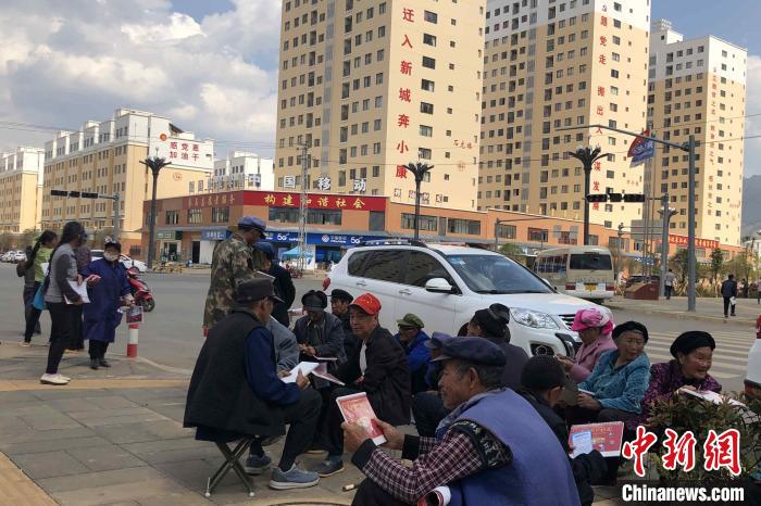 圖為會澤縣城易地扶貧搬遷安置點(diǎn)內(nèi)，老人們聚在廣場上聊天，身后是他們的新家?！】姵?攝