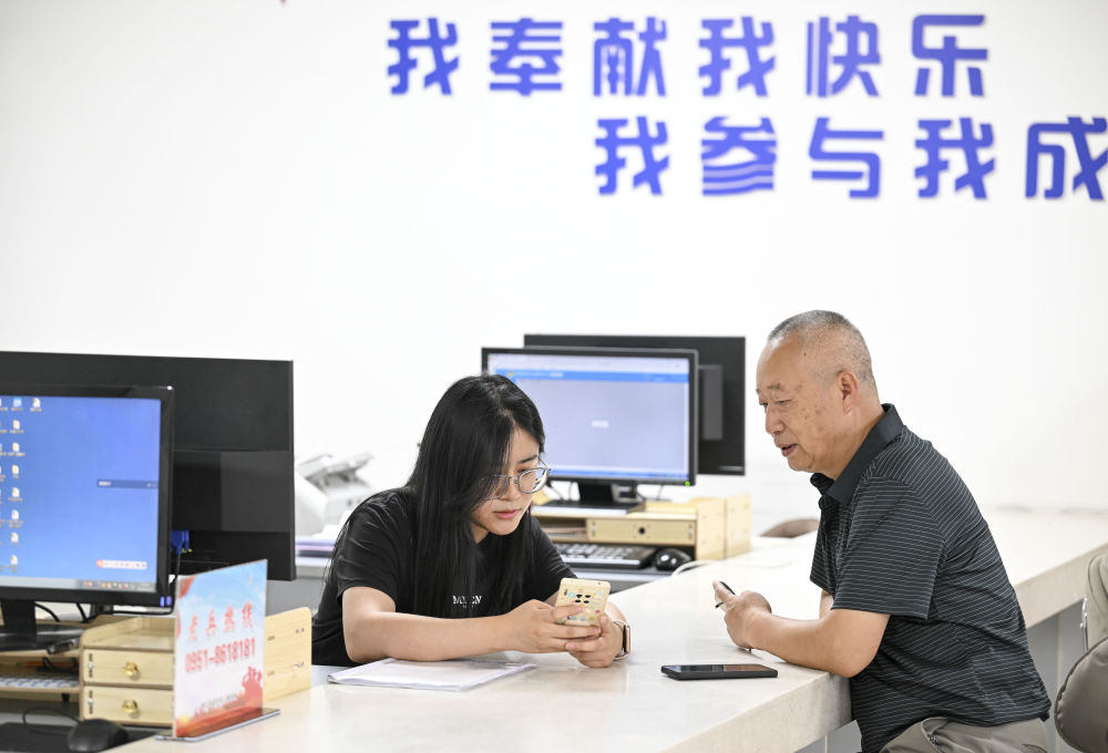 2024年6月20日，在寧夏銀川市金鳳區(qū)長城花園社區(qū)黨群服務中心，工作人員幫助居民辦理業(yè)務。圖片來源 新華社