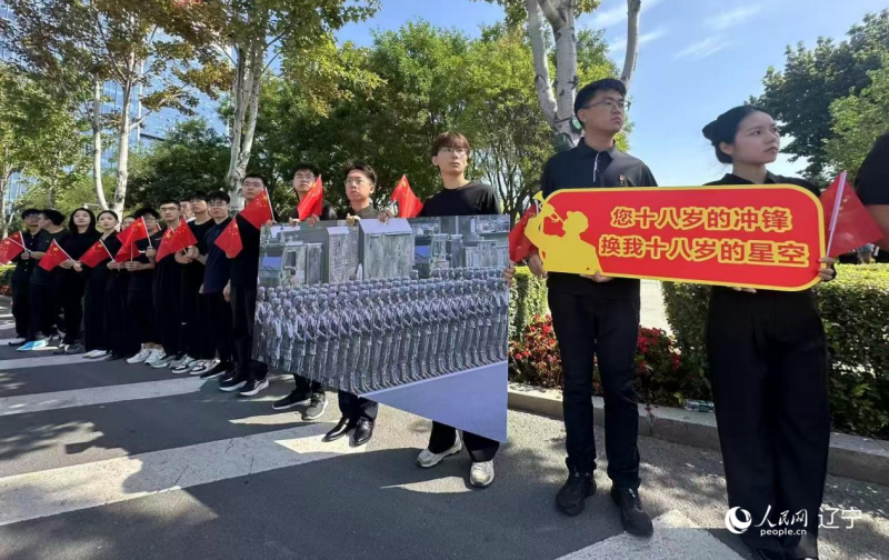 沈陽市人民廣場(chǎng)上，大學(xué)生們手持閱兵的圖片，告慰英烈。人民網(wǎng)記者 周頌雪攝