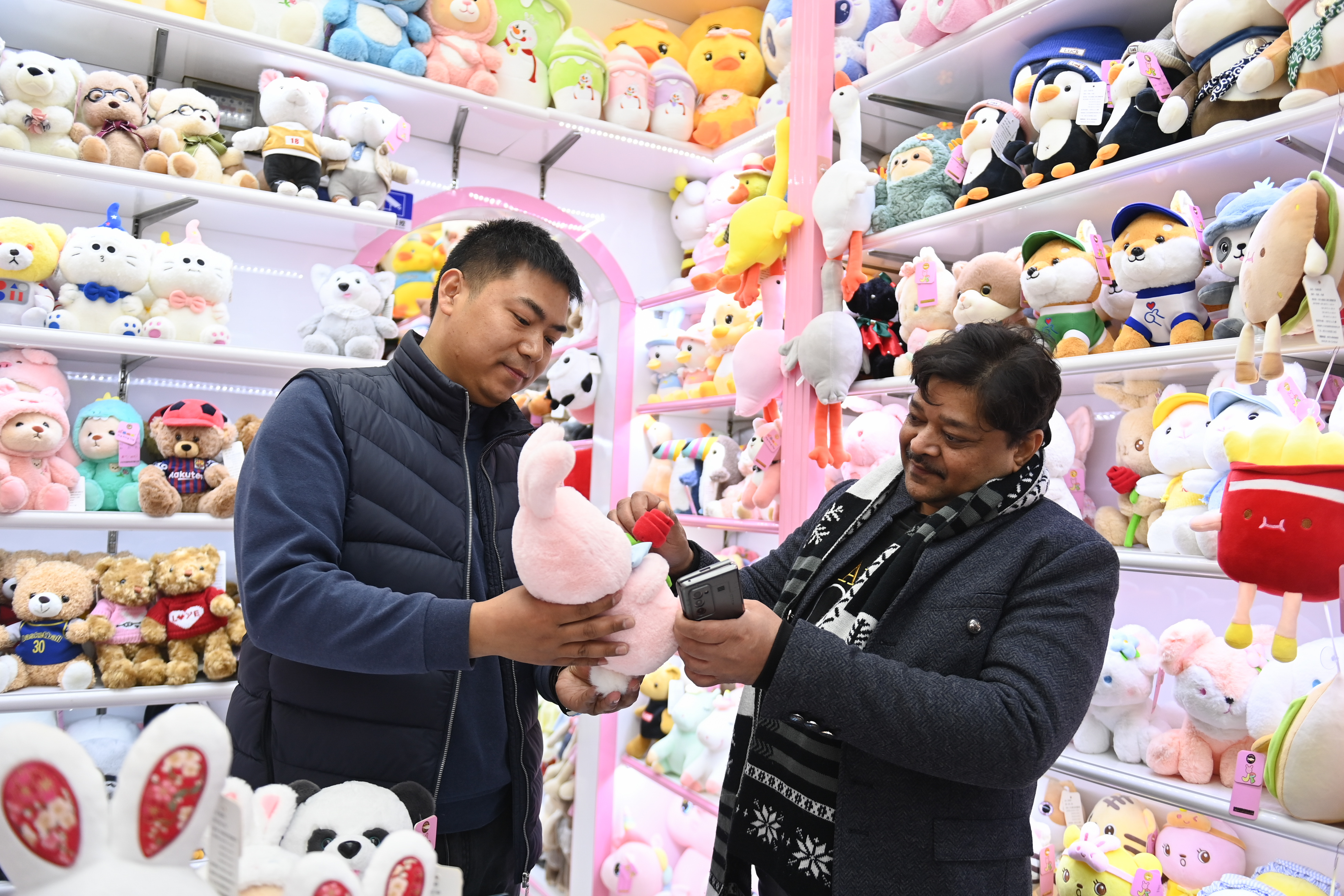 2023年2月2日，來自印度的客商（右）在義烏國際商貿(mào)城的一家玩具店鋪內(nèi)選購。