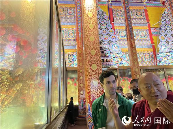 7月25日，省級(jí)非物質(zhì)文化遺產(chǎn)項(xiàng)目塔爾寺酥油花的代表性傳承人朋措堅(jiān)參（右）在塔爾寺酥油花館講解酥油花的制作過(guò)程。人民網(wǎng) 謝瑩攝