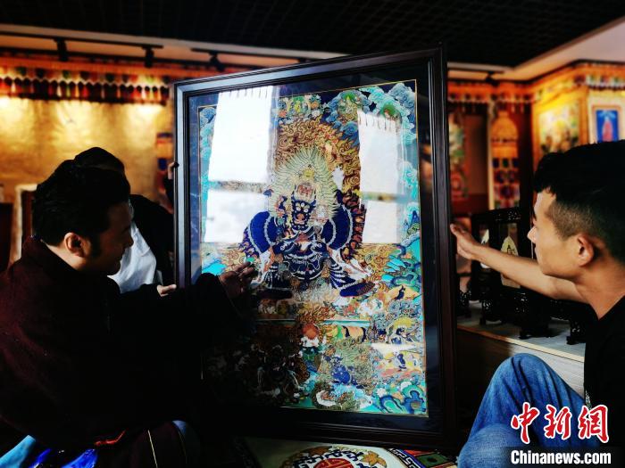 圖為久美尖措(左)與徒弟們展示唐卡作品?！?zhí)砀?攝