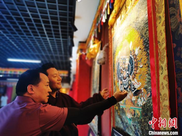 圖為久美尖措展示唐卡作品?！?zhí)砀?攝