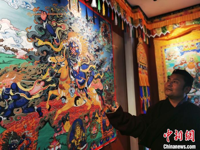 圖為久美尖措展示唐卡作品?！?zhí)砀?攝