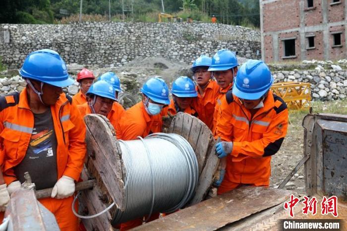 國網(wǎng)四川送變電公司搶險隊員將重達370公斤的鋼絞線搬上車。　劉湘釩 攝