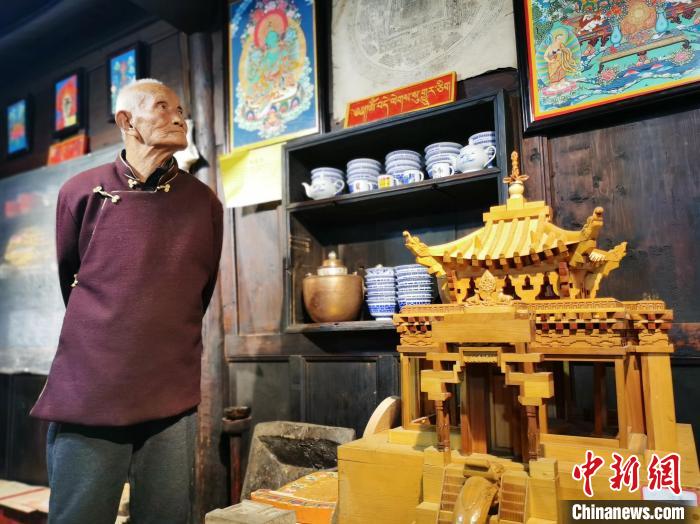 圖為古堡內(nèi)的藝人桑杰展示自己的雕刻作品?！?zhí)砀?攝