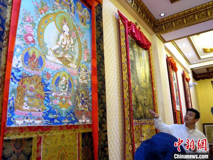 圖為完德尖措展示熱貢龍樹畫苑內(nèi)的唐卡。　張?zhí)砀?攝