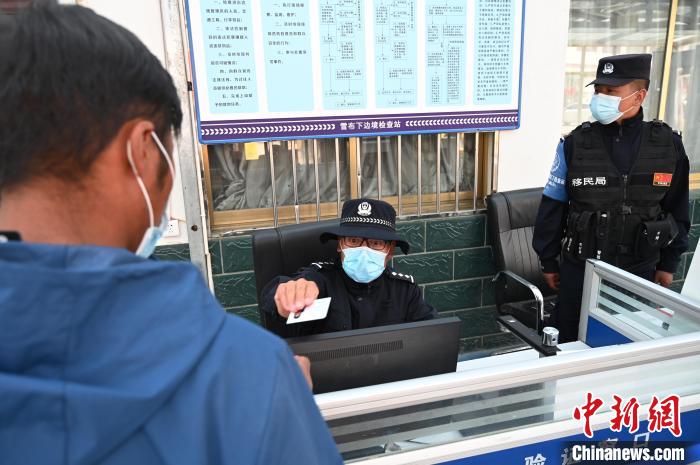圖為移民管理警察登記完身份信息后將證件歸還給行人?！≮w朗 攝