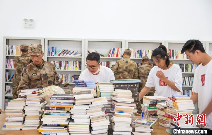 圖為志愿者們和邊防戰(zhàn)士整理圖書?！詵| 攝