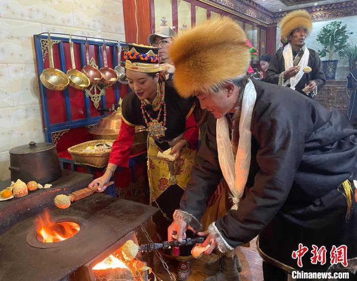 圖為人們在火上烤節(jié)日美食“結(jié)達(dá)”?！∪轿木?攝