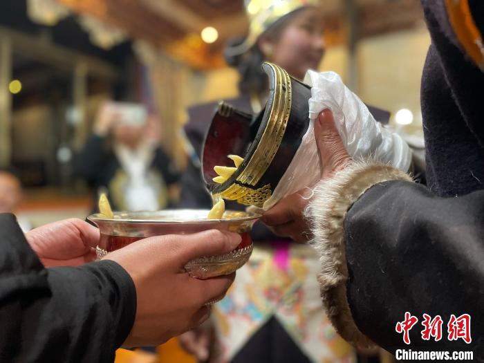 圖為主人在碗中斟滿青稞酒。　冉文娟 攝
