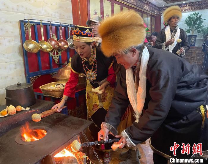 圖為人們在火上烤節(jié)日美食“結(jié)達”?！∪轿木?攝