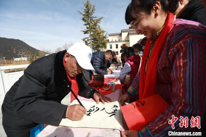 圖為林芝市文聯(lián)書(shū)法家協(xié)會(huì)會(huì)員向民眾贈(zèng)送藏文書(shū)法作品?！埩?攝