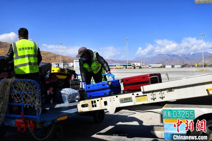 圖為機場工作人員傳送旅客行李箱?！≈芎?攝