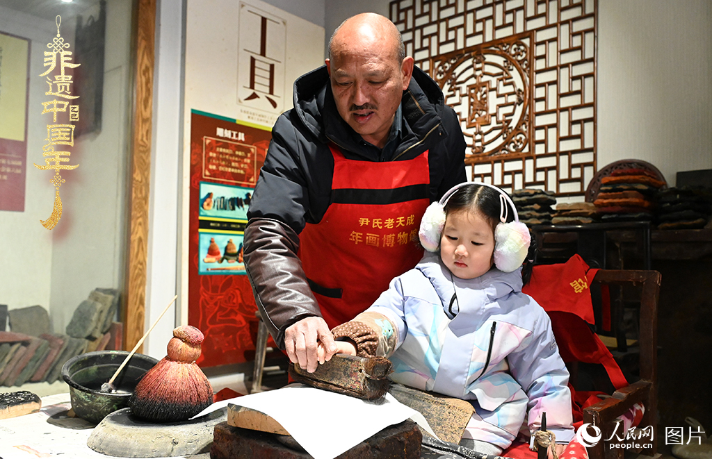 2025年1月27日，河南開封朱仙鎮(zhèn)木版年畫藝人尹國法指導小朋友研習年畫印制技藝。朱仙鎮(zhèn)木版年畫源自漢唐壁畫藝術(shù)，是中國木版年畫的鼻祖。2006年5月20日，朱仙鎮(zhèn)木版年畫經(jīng)國務院批準列入第一批國家級非物質(zhì)文化遺產(chǎn)名錄。人民網(wǎng)記者 王玉興攝