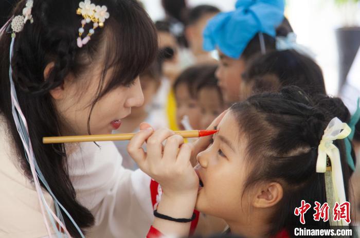 圖為老師在孩子們額頭上點(diǎn)上雄黃，驅(qū)邪辟禍?！《^生 攝
