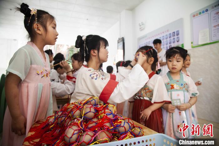 圖為幼兒園的老師們穿上漢服為小朋友們戴上彩蛋，寓意著幸福安康?！《^生 攝